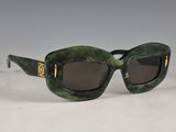 des lunettes de soleil vertes aux verres marron posées sur une surface blanche