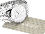 a silver watch sitting on top of a silver business card