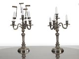 une paire de chandeliers plaqués argent avec des bougies posés sur une table en verre