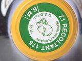 a close up of a yellow and white bottle with a green label on it