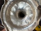 someone is holding a silver plate with a hole in it