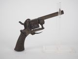 un vieux pistolet posé sur une surface blanche, dans un étui en plastique transparent