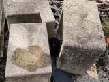 two cement blocks sitting on the ground next to a pile of wood