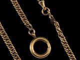 gros plan d'une chaîne en or sur laquelle est fixée une bague
