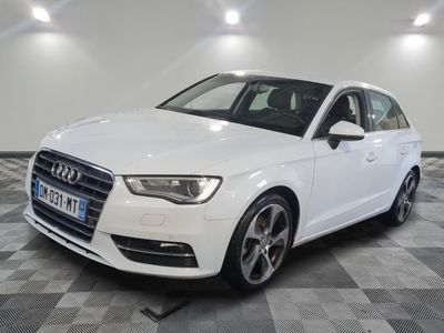 L'Audi blanche est garée dans une grande pièce au sol à carreaux.