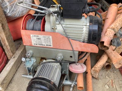 une photo d'un petit treuil électrique au milieu d'un tas de ferraille