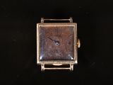a small square watch sitting on top of a black surface