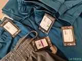 a pile of clothes with tags on them sitting on a bed