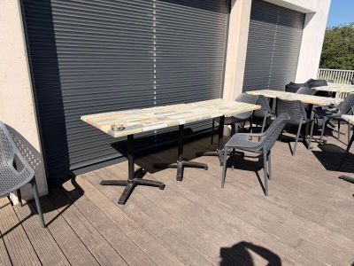 des tables et des chaises sur la terrasse à l'extérieur d'un immeuble