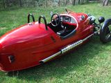 a red race car that is parked in the grass