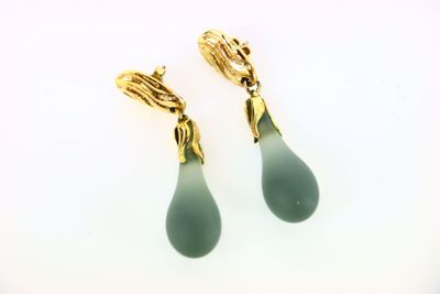 paire de boucles d'oreilles pendantes en verre vert rehaussées de touches dorées sur fond blanc