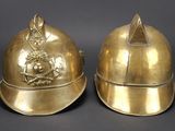 pair of antique brass helmets with a crown on each of them