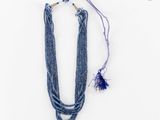 un gros plan d'un collier posé sur une surface blanche, avec un cordon violet