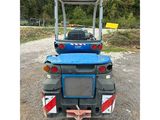 the back end of a blue tractor parked in a gravel lot