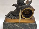 une statue représentant un ange assis au sommet d'une horloge