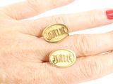 someone is holding two gold rings with the word mom on them