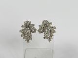 une photo d'une paire de boucles d'oreilles en diamant posées sur un socle transparent