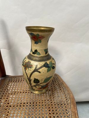 un vase posé sur une chaise en osier, posée à même le sol