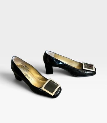 deux paires de chaussures noires et dorées posées sur une surface blanche