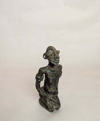 an image of a statue of a woman sitting on a white surface
