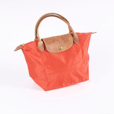 an orange purse with a brown handle on a white background