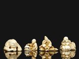 four carved ivory figurines of buddhas sitting on a rock