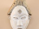 a white mask on the wall with a hat on it