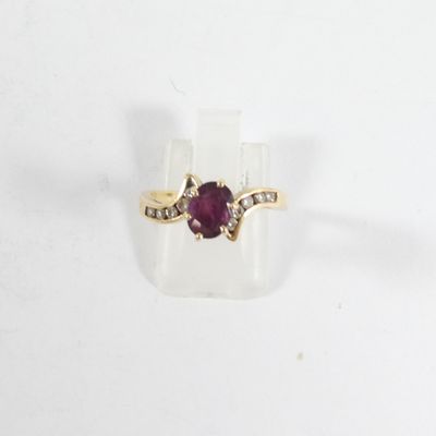 un gros plan d'une bague sertie d'une pierre rouge et de diamants