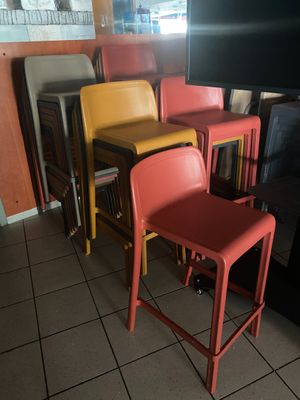 Dans un restaurant, des chaises aux couleurs vives sont alignées contre un mur