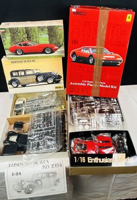 Trois modèles réduits de Ferrari dans leur boîte sont posés les uns à côté des autres sur une table