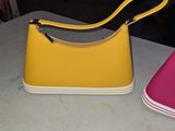 yellow and pink purses sitting on a table next to each other