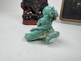 a small statue of a man sitting on a chair next to a small statue of a man