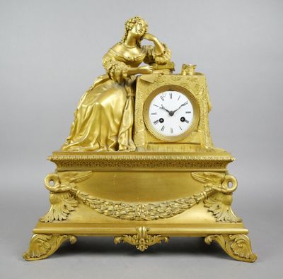 une horloge en or avec une femme assise dessus