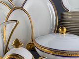 a lot of white and gold plates and bowls on a table