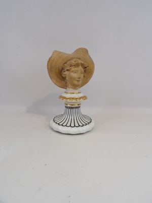 statue d'une femme coiffée d'un chapeau de paille, posée sur un socle blanc