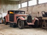 an old pink car parked in a garage with other cars