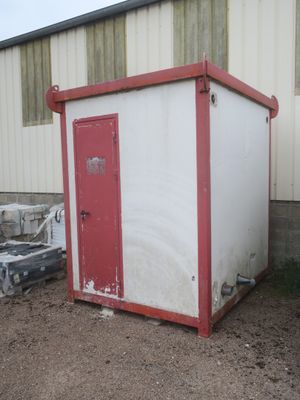 a small white and red building with a red door