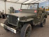 une jeep militaire garée dans une tente, avec d'autres véhicules en arrière-plan