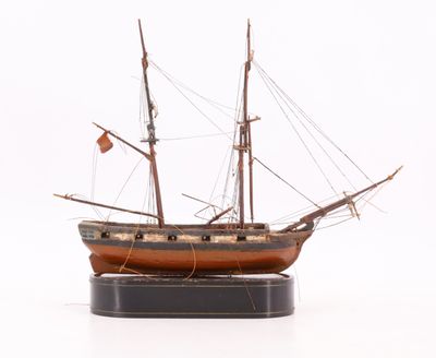 une maquette de bateau posée sur un socle, sur une surface blanche