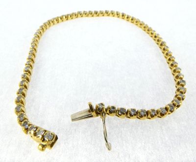 a close up of a gold bracelet with diamonds on a white surface