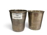 two silver cups with labels on them sitting next to each other