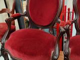 two red chairs sitting on top of a wooden table next to a mirror