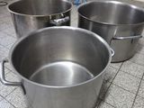 trois casseroles en métal posées sur le carrelage d'une cuisine