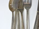 a silverware set on a white table with a knife, fork, spoon, and spoon rest