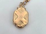 a close up of a gold keychain with a cross on it