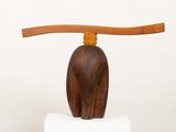 wooden sculpture of a cat with a wooden handle on top of a white pedestal