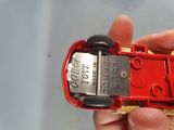 a person holding a red toy car in their hand