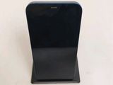 a black cell phone sitting on a stand on a table