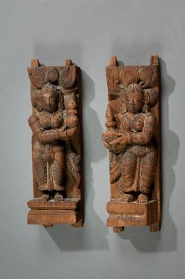 une paire de sculptures en bois représentant un homme et une femme tenant un enfant dans leurs bras