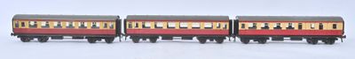 trois trains miniatures posés sur une surface blanche